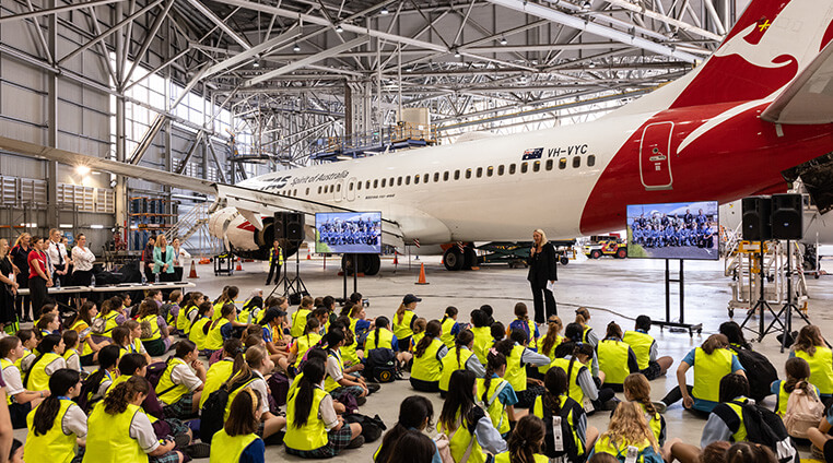 A group of school students in the hangar learning about aviation from industry professionals