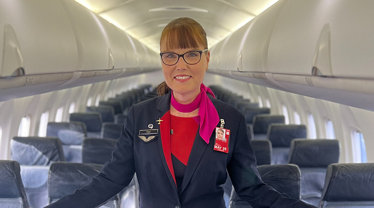 Cabin crew member in the cabin, smiling at camera